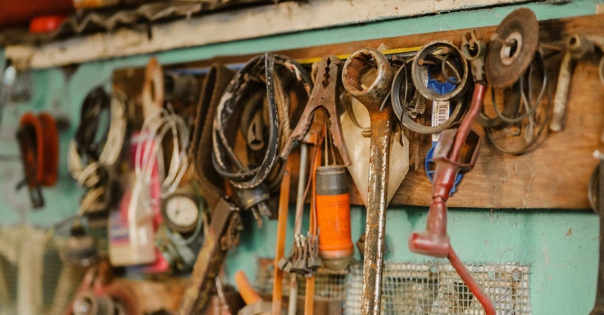 Spanners, clamps and cable hanging from a board against a mint-green workshop wall.