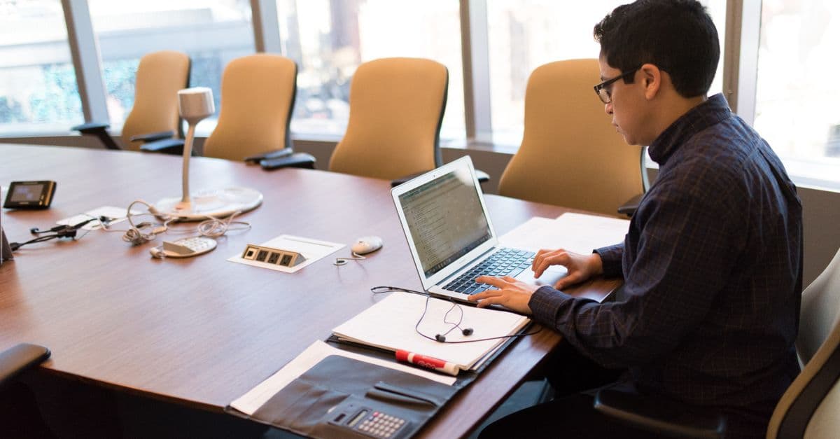 A professional working at a laptop in a bright, modern office.
