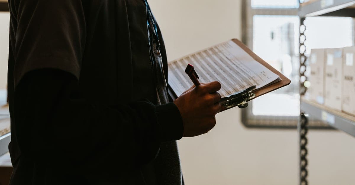 A worker in a warehouse working through a checklist on a clipboard.