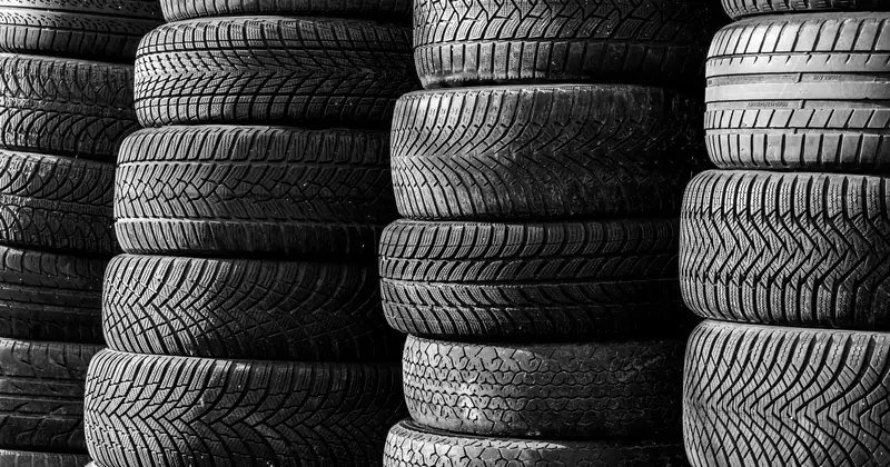Black and white image of stacked vehicle tires showcasing various tread patterns.