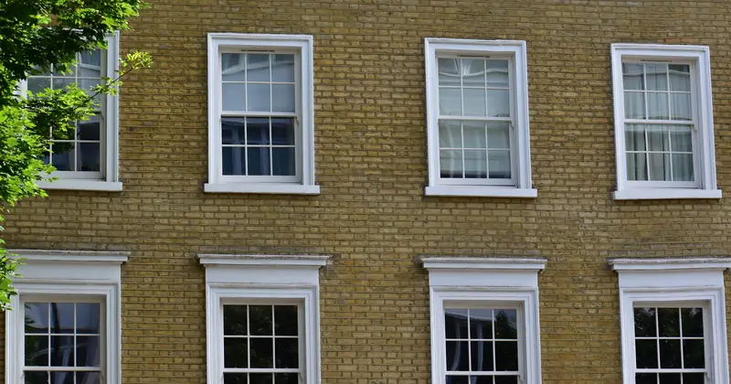 Detailed view of a vintage brick building facade with white framed windows in London.