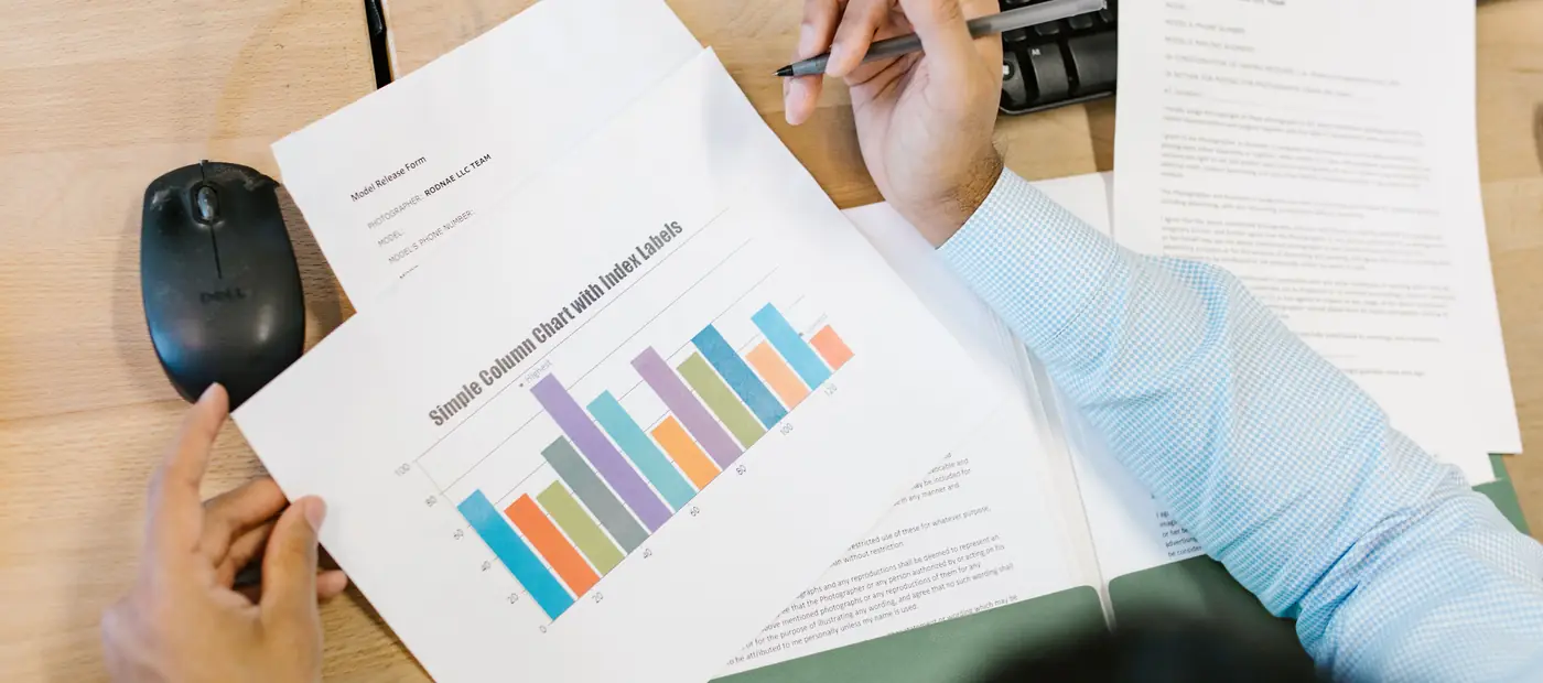 A business analyst reviews a colorful bar chart and documents at a desk, indicating data analysis.