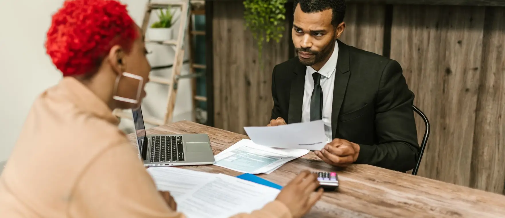 Two people discussing paperwork and figures across a desk