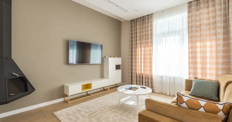Bright modern living room with a sofa, coffee table, and large window curtains.
