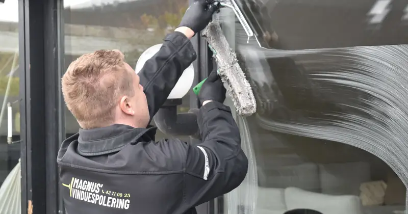 Professional cleaning service washing a large glass window. Clean and efficient work by a dedicated individual.
