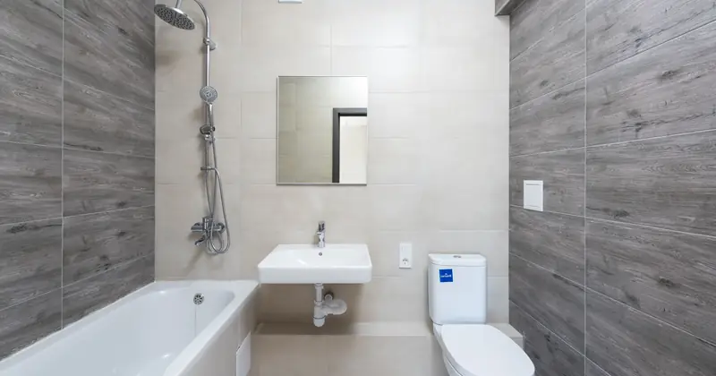 A contemporary bathroom features a bathtub, sink, and toilet with wood accents.