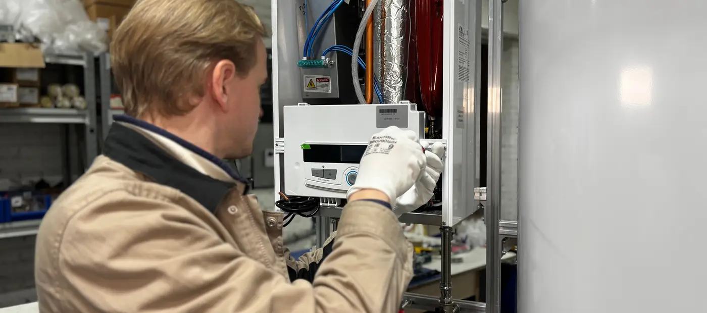 Technician installing or repairing a heating system in an indoor workshop setting.