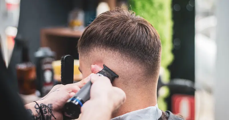 A barber skillfully trims a young man's hair in a modern salon setting, showcasing expertise and precision.