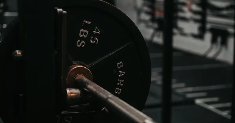 Detailed close-up of a heavy barbell loaded with a 45 lbs weight plate in a gym setting.