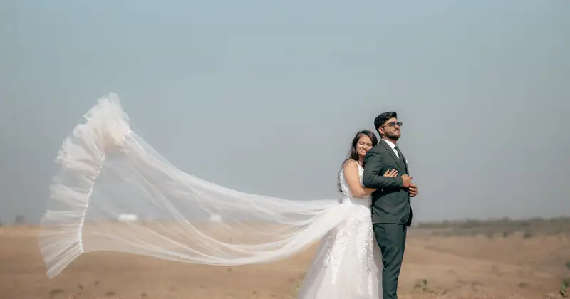 Smiling couple in wedding attire holding hands amidst forest trees, conveying joy and love.
