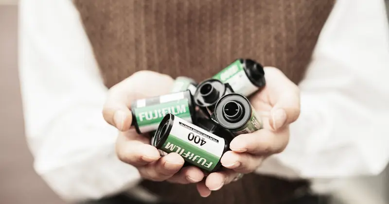 Close-up of hands holding multiple Fujifilm 400 film rolls, symbolizing vintage photography.
