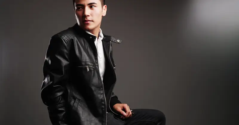 Elegant and modern portrait of a man wearing a black leather jacket in a studio setting.