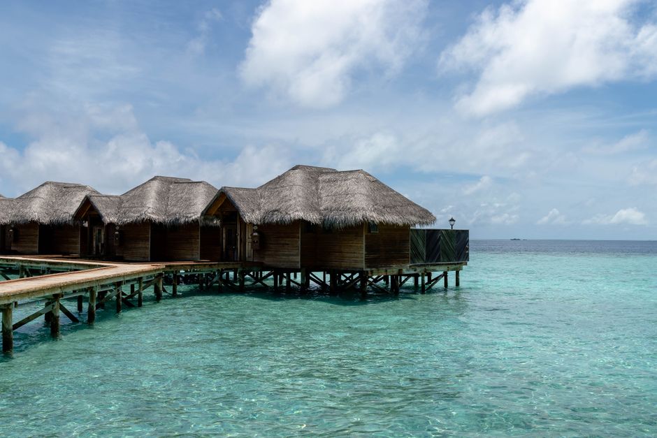 Overwater villas above clear lagoon water in the Maldives.