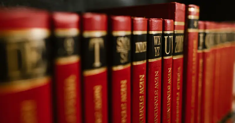 Close-up view of red leather bound encyclopedias on a bookshelf in a library.