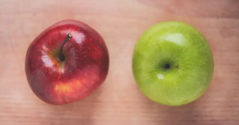 Close-up of a red and a green apple on a wooden table, ideal for healthy eating themes.