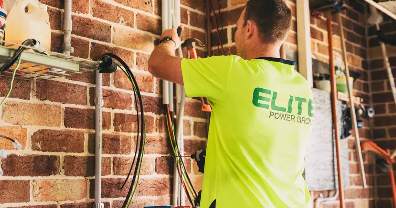 Electrician performing solar battery installation for sustainable energy storage in a home setting.