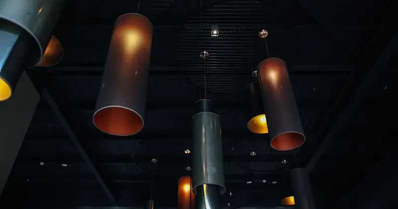 A low angle shot showcasing industrial style pendant lights against a dark ceiling, creating a moody atmosphere.