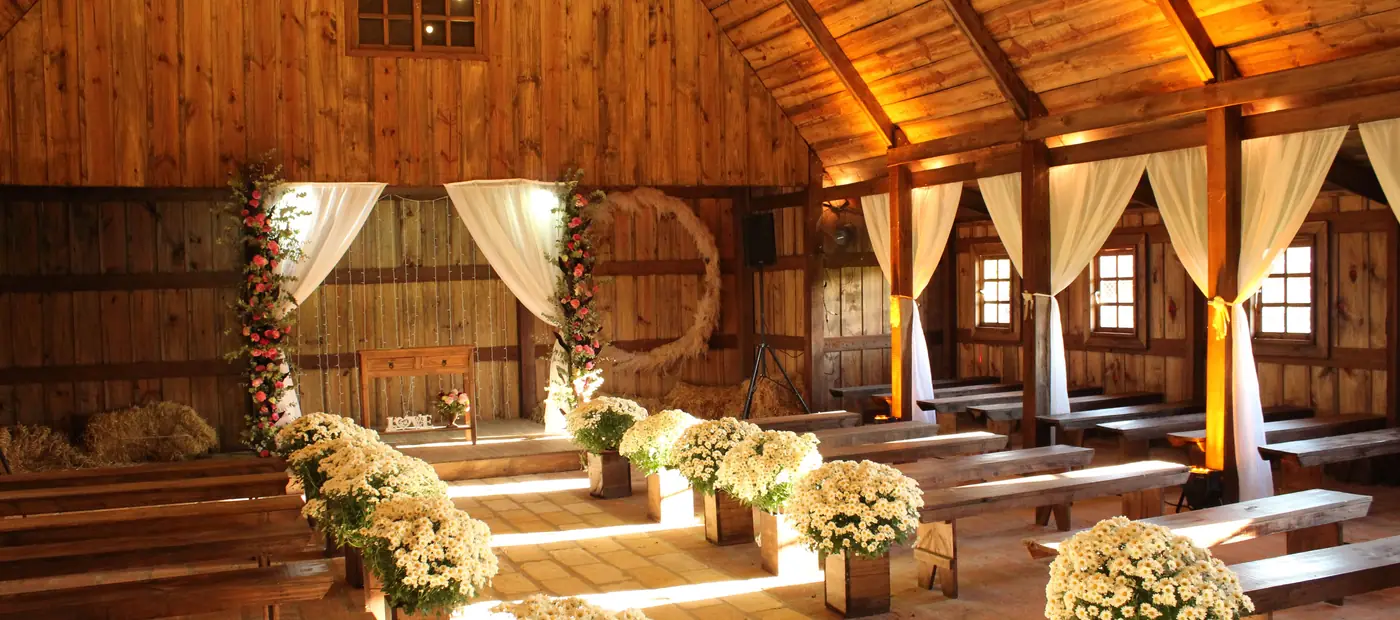 Charming wooden barn decorated for a wedding with floral arrangements and soft lighting.