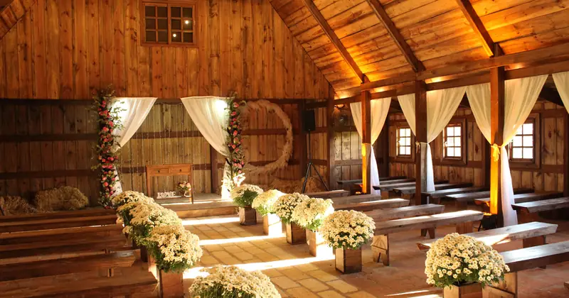 Charming wooden barn decorated for a wedding with floral arrangements and soft lighting.